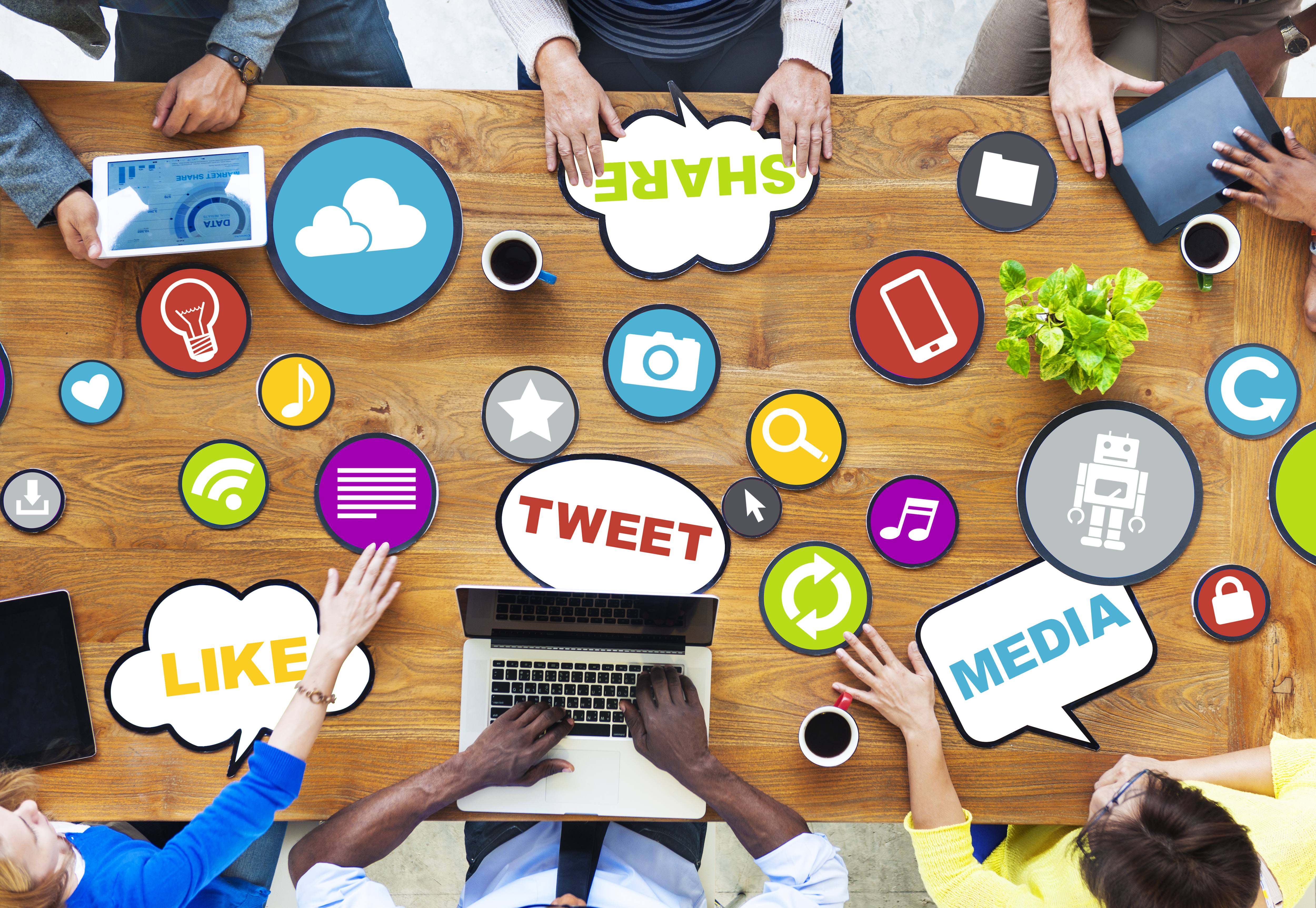 An areial view of people around a table, filled with various social media symbols and icons